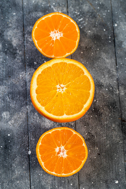 chopped oranges in half on a wooden table - Fotografie, Obrázek