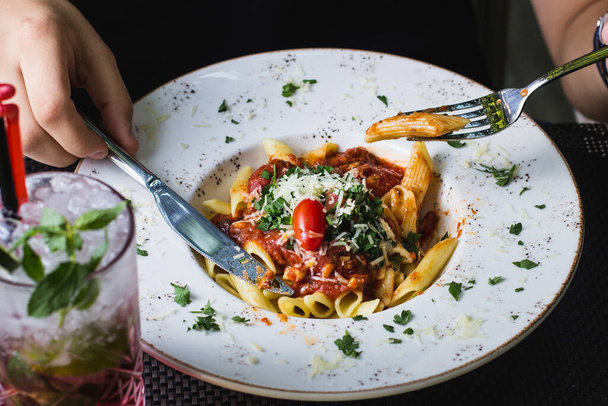 man eating bolognese penne pasta garnished with herbs - 写真・画像