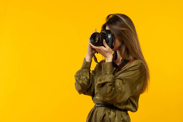 γυναίκα χρησιμοποιεί κάμερα στο κίτρινο δωμάτιο - Φωτογραφία, εικόνα