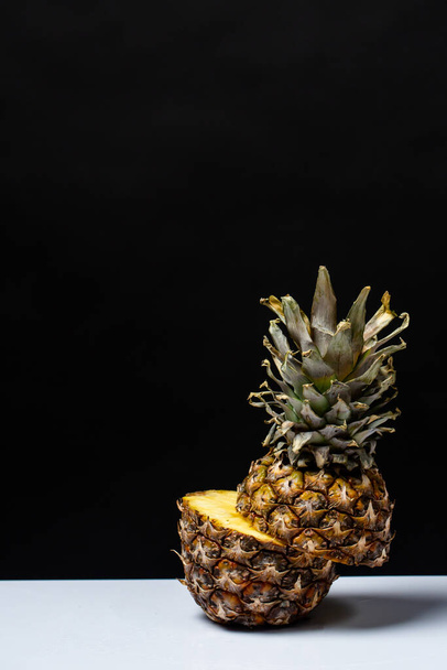 pineapple cut in half on a table on a black background - Фото, изображение