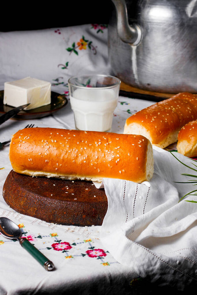 long pastry bun with sesame sprinkles served with milk - Fotografie, Obrázek