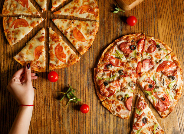 sliced pieces mixed pizza with sausage and pizza with cheese and tomatoes - 写真・画像