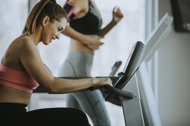 Pretty young woman using treadmill in modern gym - Foto, Imagen