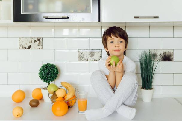 Little boy in the kitchen with a bowl of fresh fruits - Foto, immagini