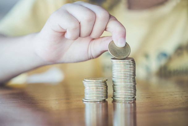 Saving money concept preset ,coins in finger and row stacks on table. - 写真・画像