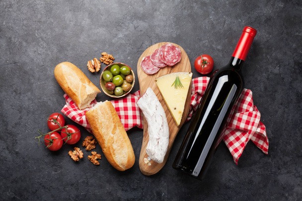 Jídlo italské kuchyně. Chléb, sýr, salám, olivy a víno. Horní pohled plochý ležel na kamenném stole - Fotografie, Obrázek