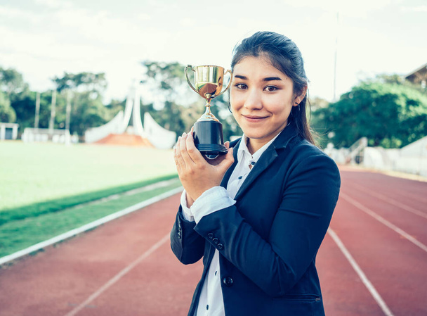 ділова азіатська жінка тримає трофей на стадіоні
. - Фото, зображення