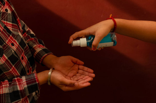 Cortar la mano con la botella desinfectante para limpiar las manos con fondo rojo
 - Foto, Imagen