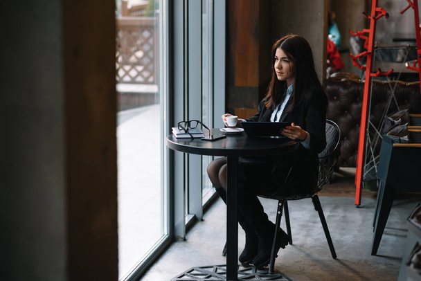 Happy young businesswoman using tablet computer in a cafe. Selective focus. - 写真・画像