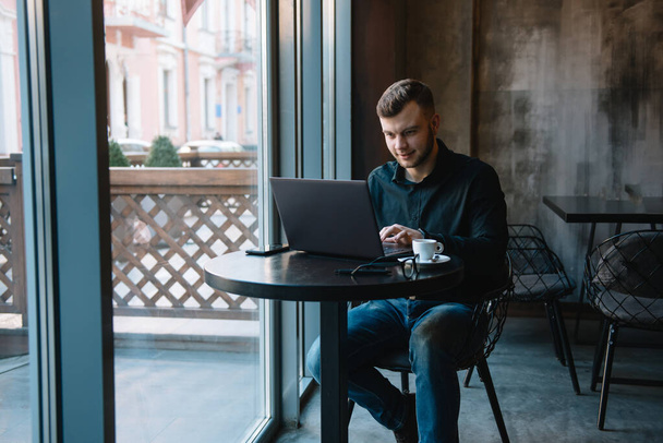 Young successful businessman working on a laptop while sitting in cafe. - Foto, immagini