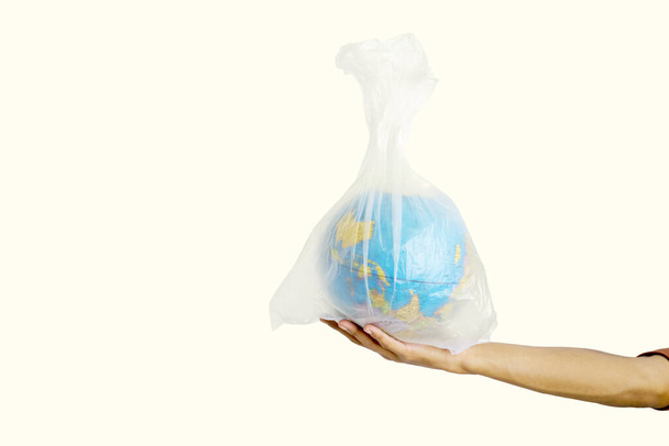 Human hand holding globe in plastic bag in the studio, isolated on white background - Photo, image