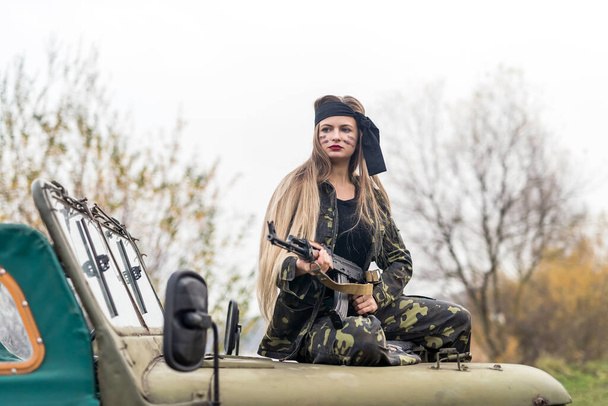 若いです女性兵士ライフルを持つ軍の車の上にポーズ - 写真・画像