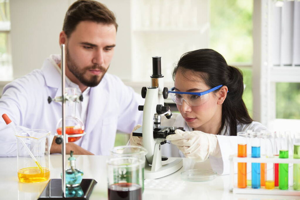 Naukowcy pracują w laboratoriach naukowych.Zbliżenie naukowca, Młodego naukowca patrzącego przez mikroskop w laboratorium prowadzącym badania, medycyna analizy mikrobiologicznej dla kovid19. - Zdjęcie, obraz