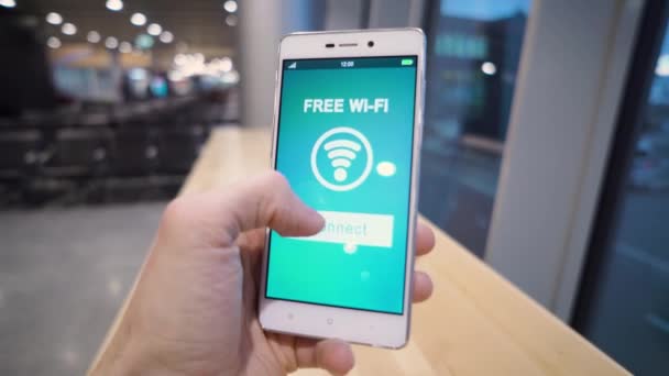 Hand hält Smartphone mit kostenlosem Wifi-Zeichen auf dem Bildschirm über verschwommenem Hintergrund, Geschäfts- und Technologiekonzept - Filmmaterial, Video