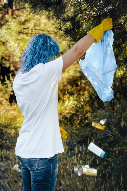 A female emptying the plastic garbage bag in a green environment - plastic pollution concept - Fotoğraf, Görsel
