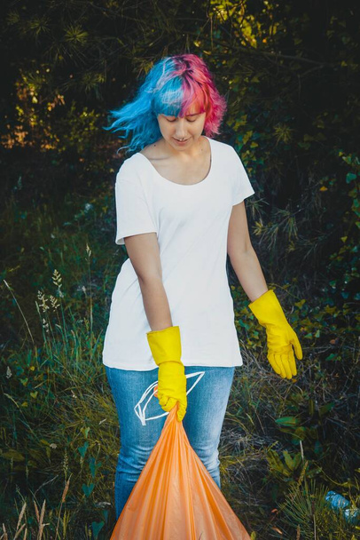 Uma mulher voluntária com um saco de lixo a limpar o ambiente da poluição plástica - Foto, Imagem