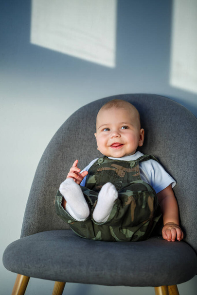 全体で8ヶ月の小さな男の子白いシャツと白い靴下灰色の椅子に座って - 写真・画像