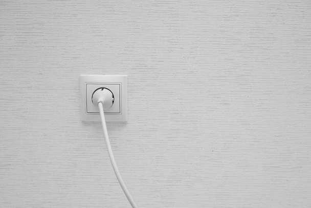 White electrical plug in the electric socket on a wall. - Photo, Image