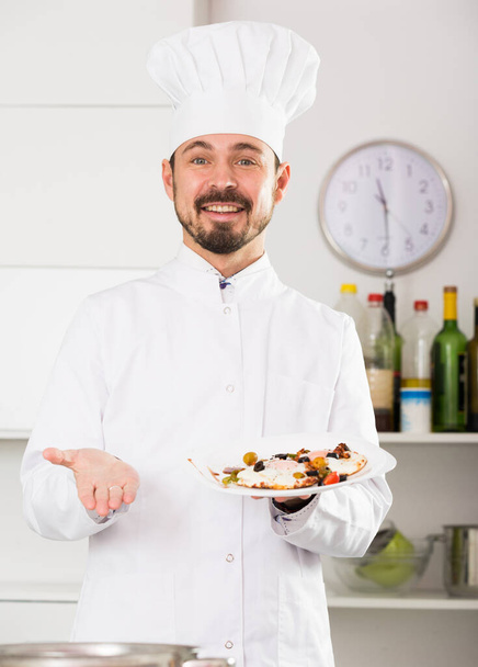 Young male cook preparing delicious food in kitchen - Photo, Image