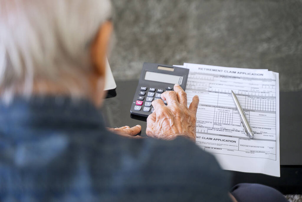 Senior man calculating his savings with retirement form on the table - Foto, Bild