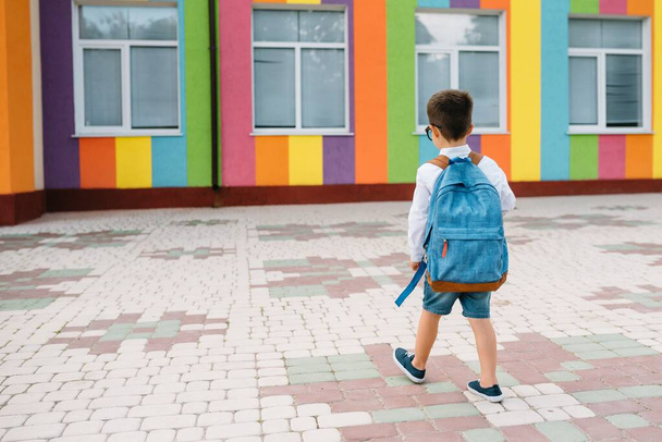A kisfiú visszamegy az iskolába. Gyerek hátizsákkal és könyvekkel az első tanítási napon. Visszanézni. Iskolai koncepció. Vissza az iskolába.. - Fotó, kép