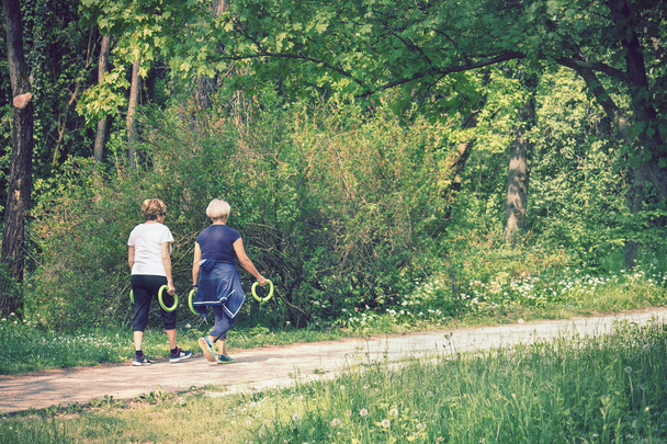 Panie ćwiczące z ciężarkami na świeżym powietrzu, dwie kobiety w średnim wieku robiące zdrowy wypoczynek - Zdjęcie, obraz