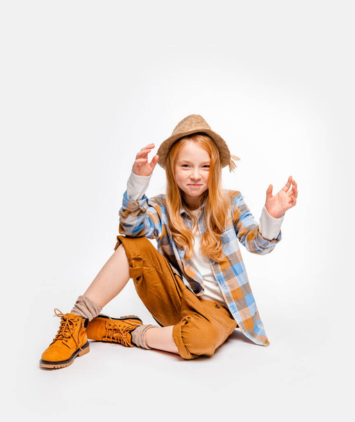long-haired emotional girl in traveler clothes sits on the floor - Foto, afbeelding