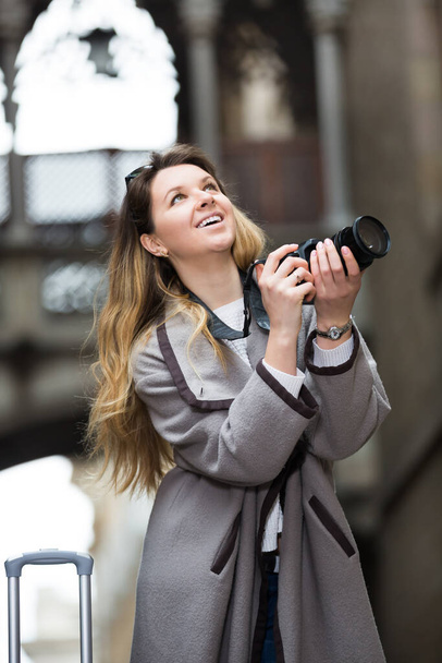 Young positive cheerful woman looking curious and taking the pictures outdoors  - Фото, изображение