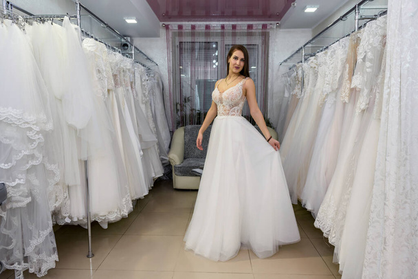 Young and tiny bride in wedding dress in salon - Фото, изображение