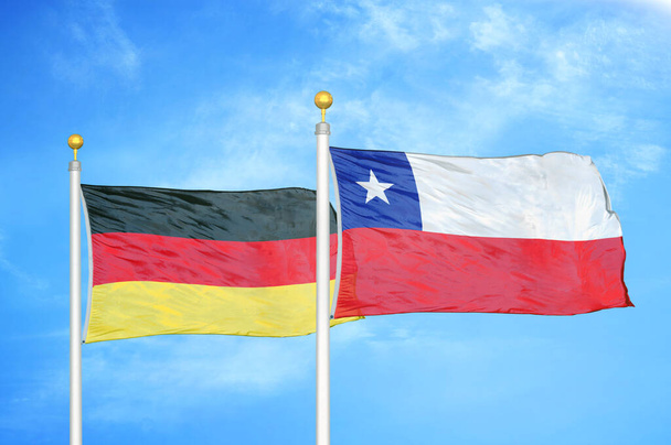 Німеччина і Чилі два прапори на флагштоках і синє хмарне небо. - Фото, зображення
