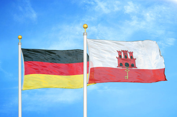 Saksa ja Gibraltar kaksi lippua lipputangoilla ja sininen pilvinen taivas tausta
 - Valokuva, kuva