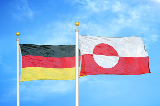 Германия и Гренландия два флага на флагштоках и голубом облачном фоне неба
 - Фото, изображение