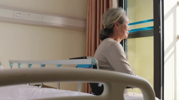aasialainen vanha nainen istuu pyörätuolissa huoneessaan hoitokodissa näyttäen onnelliselta ja tyytyväiseltä
 - Materiaali, video