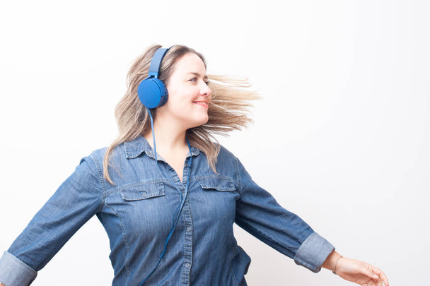 happy blonde woman listening to music shaking her head in a white background. Image with a great copy space. - Φωτογραφία, εικόνα