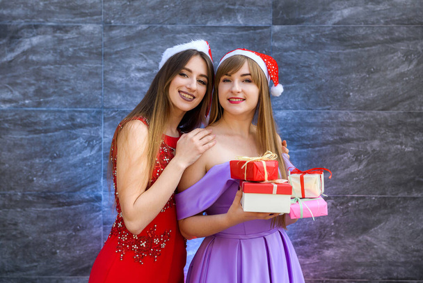 Chicas de moda en elegantes vestidos de noche posando con cajas de regalo. Año nuevo concepto de celebración
 - Foto, Imagen