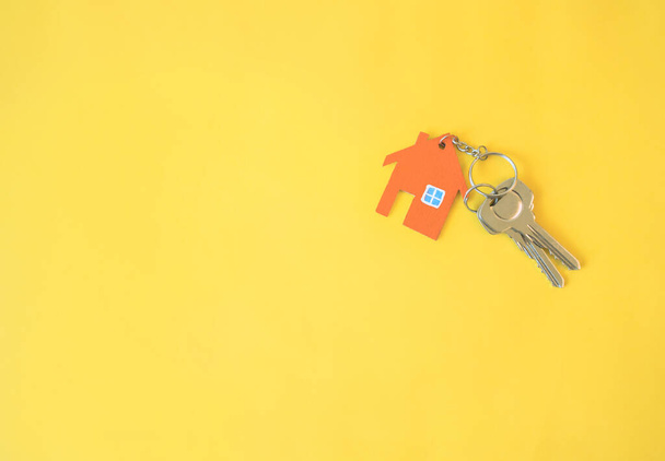 Σπίτι και κλειδί σε κίτρινο φόντο. Ελάχιστο δημιουργικό στυλ. - Φωτογραφία, εικόνα