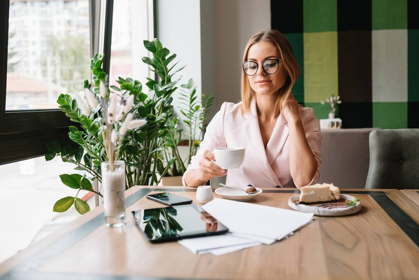beautiful business lady drinking coffee and uses different gadgets - Foto, afbeelding
