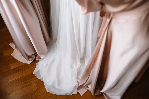 Bridesmaid preparing bride for wedding day. Bridesmaid helping bride fasten lacing her wedding white dress before ceremony. Luxury bridal dress close up. Wedding morning moments details concept - Foto, Imagen