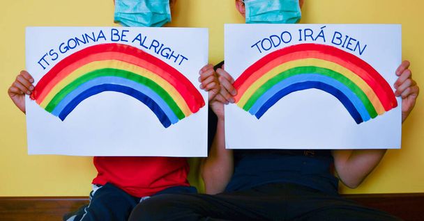 Broeders dragen een wegwerp groen masker met boodschap van hoop en regenboog op vellen papier voor zich. - Foto, afbeelding