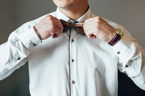 Beyaz gömleğin arka planında erkek elleri kol düğmeleri ve saatlerle kol gömleği, yakın plan çekimleri. - Fotoğraf, Görsel