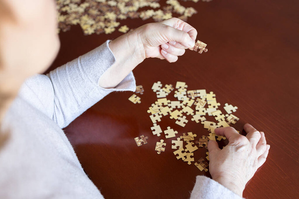Hands and jigsaw puzzle pieces on a table - Photo, Image
