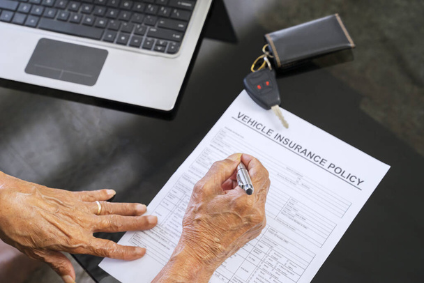 Senior man hand filling a vehicle insurance form on the table at home - Φωτογραφία, εικόνα