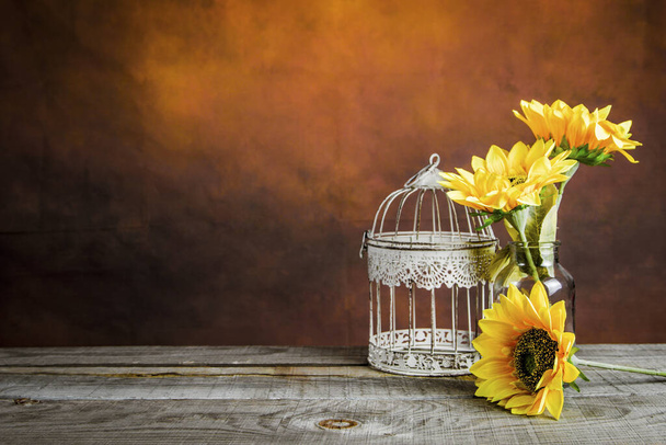Krásné slunečnice s ptačí klecí na dřevěném stole s vinobraním pozadí - Fotografie, Obrázek