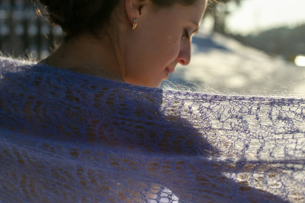 una chica de pelo oscuro con un perfil elegante está de pie con su espalda a la cámara con un chal de encaje púrpura sobre sus hombros
 - Foto, Imagen