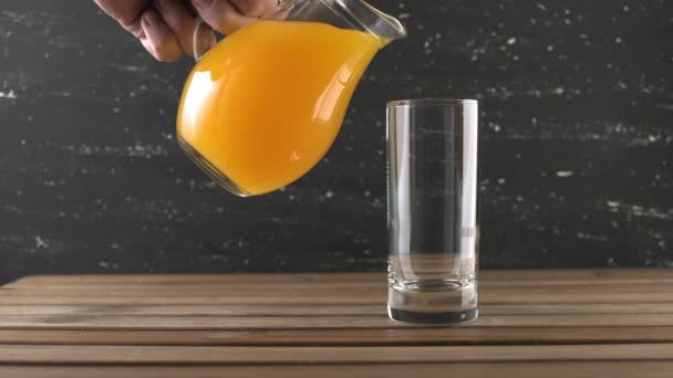 Orange juice being poured in tall glass. Pouring orange juice into glass - Filmati, video