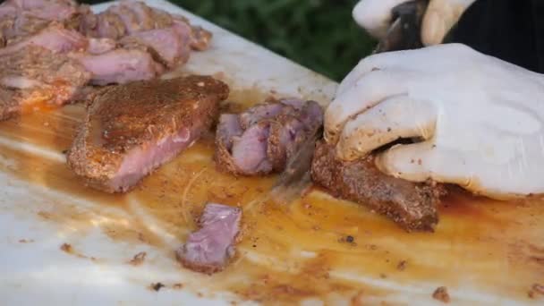 Közelíts rá a kezedre egy füstölt marhaszegyet tartva egy vágódeszkán, és gyorsan szeleteld vékony szeletekre a főtt marhahúst egy grillezéshez.. - Felvétel, videó