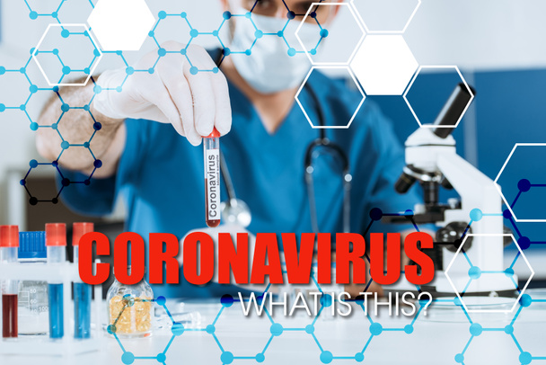επιλεκτική εστίαση του επιστήμονα στην ιατρική μάσκα και γάντια λατέξ κρατώντας δοκιμαστικό σωλήνα με επιγραφή coronavirus - Φωτογραφία, εικόνα