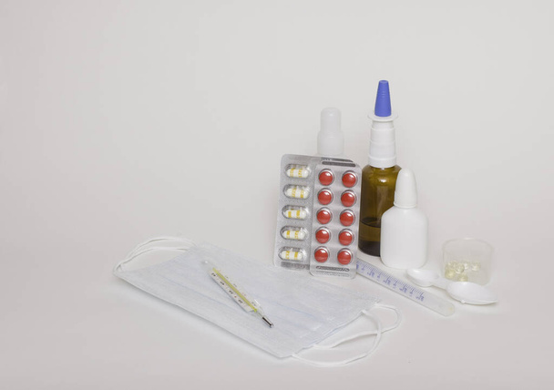 Médicaments, comprimés, thermomètre, masques médicaux sur fond blanc. Espace libre pour le texte, vue latérale
. - Photo, image