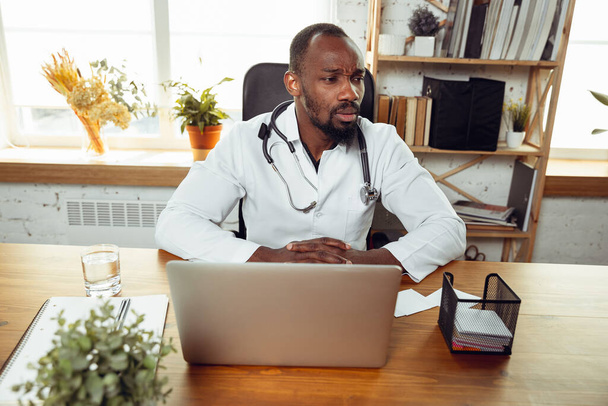 Африкансько-американський лікар, який консультує пацієнта, працює в кабінеті - Фото, зображення