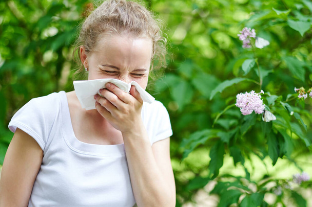 Pollen allergy, girl sneezing with bouquet of flowers. Concept: seasonal allergy. - Valokuva, kuva